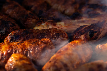 Pork chops, steak, sausages on barbecue grill with smokeの写真素材