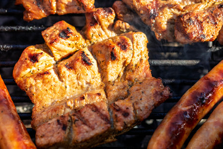 Pork chops, steak, sausages on barbecue grill with smokeの写真素材