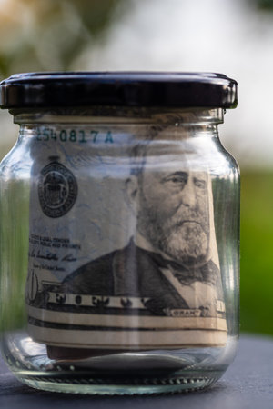 US dollar banknote saving money in glass jar. Consumption and economy. Business, tips, finance, saving, banking and people conceptの写真素材