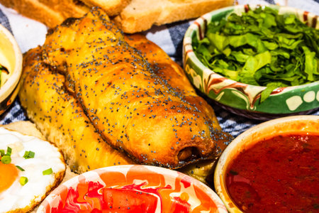 Rustic composition with sausages rolls, fried egg on toast bread, different bowls with sauce and chopped vegetables.の写真素材