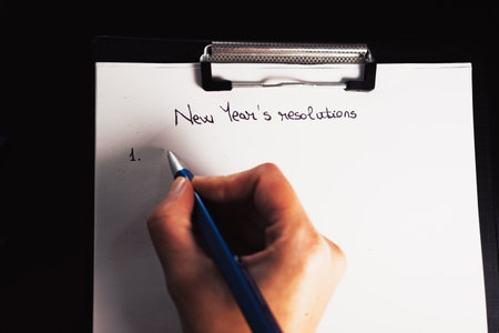 Writing New Year`s Resolutions for Christmas. Christmas Resolutions. Text New Year`s Resolutions on paper.の写真素材