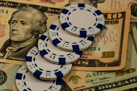 Stack of poker chips over american dollar bills and playing cards representing casino gambling and...