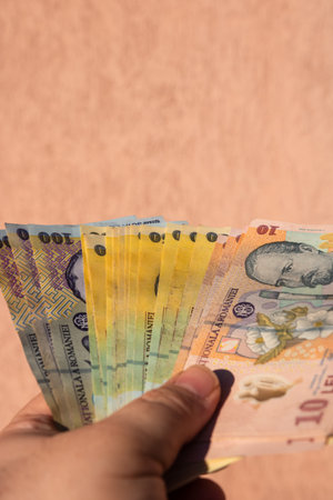 Man hand holding Romanian money banknotes, showing paper texture and symbols of Romanian LEI currencyの写真素材