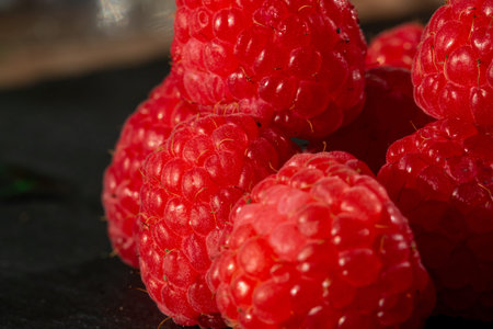 Fresh appetizing ripe raspberries in a detailed macro shot showing texture and vibrant red raspberry...