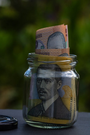Romanian LEI banknote saving money in glass jar. Consumption and economy. Business, tips, finance,...