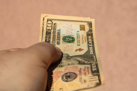 Man hand holding United States Dollar banknotes showing paper texture and symbols of American  USD...