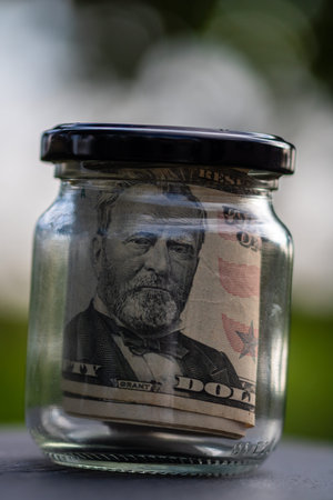 US dollar banknote saving money in glass jar. Consumption and economy. Business, tips, finance, saving, banking and people conceptの写真素材