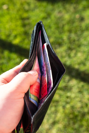 Man hand holding a wallet with Swiss Franc banknotes showing paper texture and symbols of Swiss CHF...