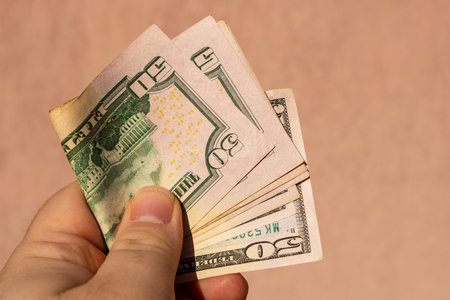 Man hand holding United States Dollar banknotes showing paper texture and symbols of American  USD...