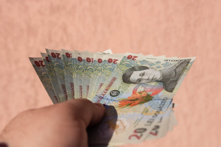 Man hand holding Romanian money banknotes, showing paper texture and symbols of Romanian LEI...