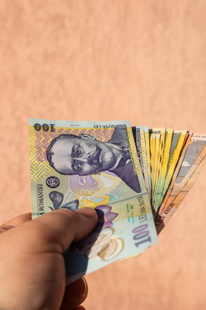 Man hand holding Romanian money banknotes, showing paper texture and symbols of Romanian LEI...
