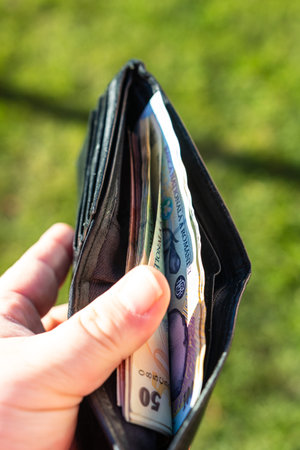 Man hand holding a wallet with Romanian LEI banknotes showing paper texture and symbols of Romanian...