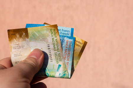 Man hand holding Swiss Franc money banknotes, showing paper texture and symbols of Swiss CHF...