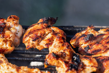 Pork and chicken steak grilling on charcoal barbecue with open flames outdoor cooking scene