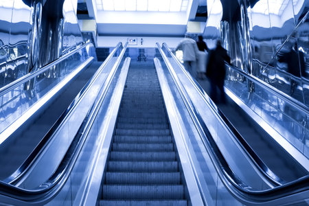 persons at the top of moving escalator in office center