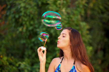 Pretty woman inflating soap-bubbles