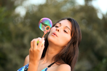 Pretty woman inflating soap-bubbles 