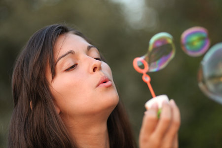 Pretty woman inflating soap-bubbles 
