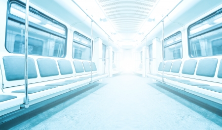 Perspective wide angle view of modern light blue illuminated and spacious public metro marble station with fast blurred trail of train in vanishing traffic motionの写真素材
