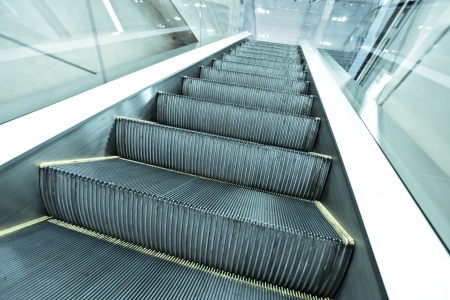 Wide angled view to perspective escalators stairway inside contemporary blue glass business centre, concept of successful career elevationの写真素材