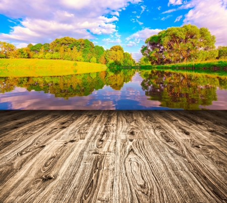 Light picturesque scene of beautiful rural lake in sunny summer park over blue sky with first dawn rays on the wall inside room interior with frame textured wooden brown panel floor backgroundの写真素材