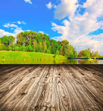 Light picturesque scene of beautiful rural lake in sunny summer park over blue sky with first dawn rays on the wall inside room interior with frame textured wooden brown panel floor backgroundの写真素材