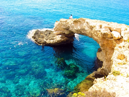 View to a rocky beautiful coast among blue bright transparent water of the sea with sky reflection in sunny dayの写真素材