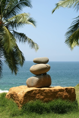 Pile of pebble Stones against the background of palm trees and the seaの写真素材