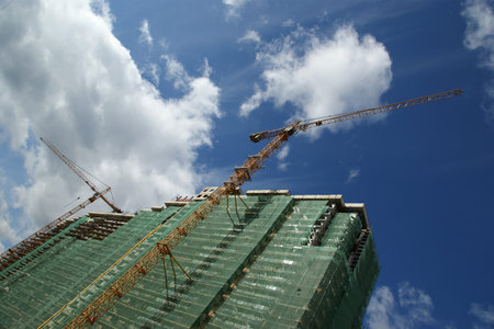 Building crane at the background of a multi-storey building under construction