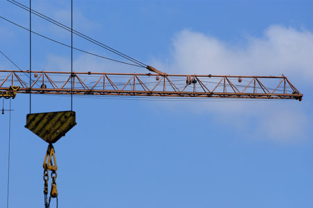 Elevating construction crane against the blue sky in a fair weatherの写真素材