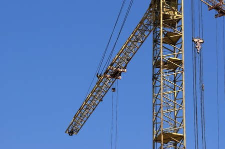 Elevating construction crane against the blue sky in a fair weatherの写真素材