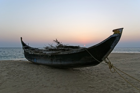 boat on the ocean shore at sunset. Kerala, Indiaの写真素材