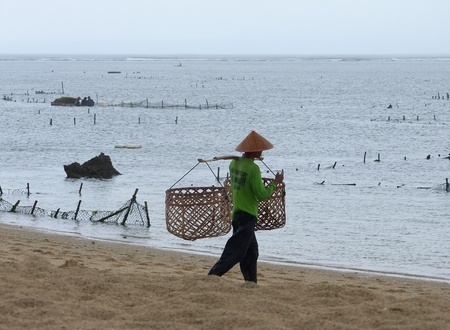 Local residents (natives), Indonesia, island Bali. The fisherman with baskets for fish on seacoast.の写真素材