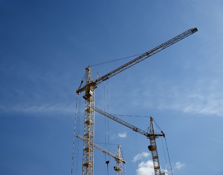 Elevating construction crane against the blue sky in a fair weatherの写真素材