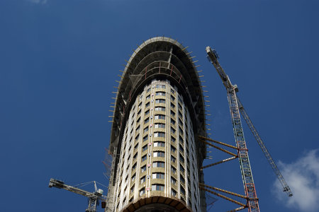 Building crane at the background of a multi-storey building under construction
