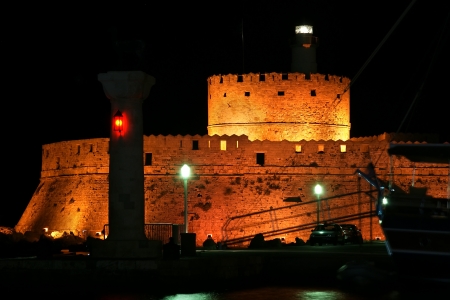 Tower of St. Nicholas in Rhodes (Greece) by night - Bluelight. Motion blur on greek flag and sail masts. Original colors.のeditorial素材