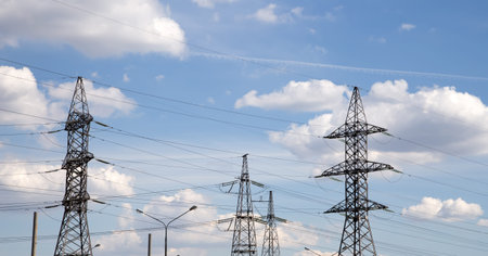 Electricity pylons and line against the blue sky and clouds