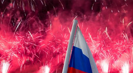 Celebratory colorful fireworks exploding in the skies and Russia flag waving in the wind against the sky. Three colors of Russian wavy flag as a patriotic symbolの写真素材
