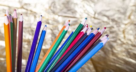 Assortment of coloured pencils on yellow (gold) backgroundの写真素材