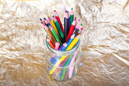 Assortment of coloured pencils on yellow (gold) backgroundの写真素材