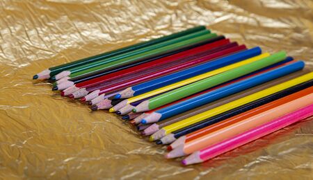 Assortment of coloured pencils on yellow (gold) backgroundの写真素材