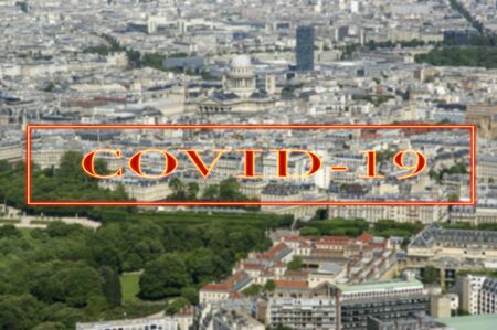 Coronavirus in Paris, France. Covid-19 sign on a blurred background. Concept of COVID pandemic and travel in Europe. The city skyline at daytime.の写真素材