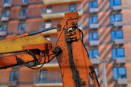 Part of a construction machine (excavator or crane) with multi-storey building under construction...