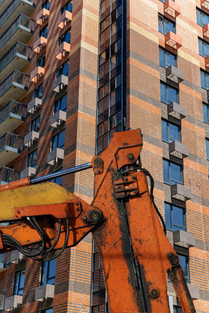 Part of a construction machine (excavator or crane) with multi-storey building under construction...