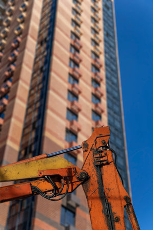 Part of a construction machine (excavator or crane) with multi-storey building under construction...