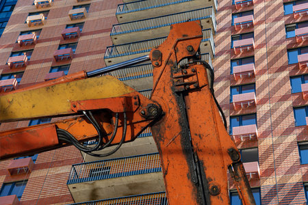 Part of a construction machine (excavator or crane) with multi-storey building under construction...