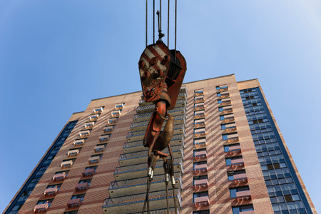 Construction crane hook with multi-storey building under construction (new residential complex) on...