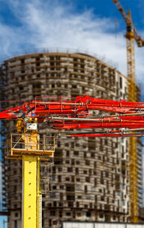 Construction concrete pump (pump truck) with multi-storey building under construction with scaffolding (new residential complex) on the background, Moscow, Russiaの写真素材