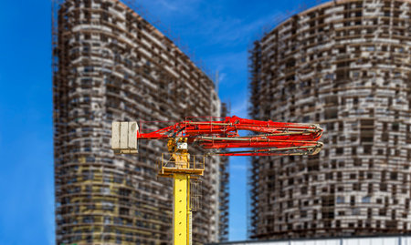 Construction concrete pump (pump truck) with multi-storey building under construction with...