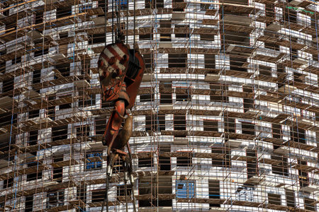 Construction crane hook with multi-storey building under construction with scaffolding (new...